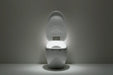 A white Neorest nx2 smart toilet with its lid open, illuminated by a built-in light on the seat. The toilet is centered against a dark gray background with the light casting a soft glow on the floor.