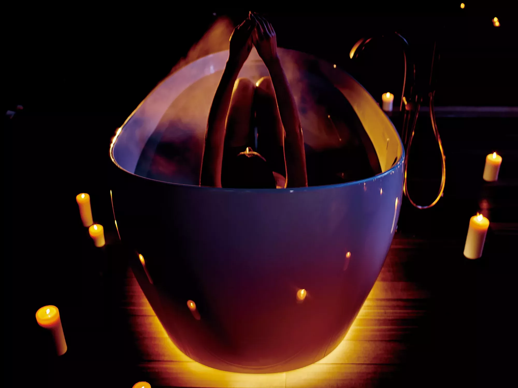 TOTO Flotation Tub With ZERO DIMENSION - Person in a bathtub with candles around, creating a relaxing atmosphere.