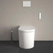 Duravit SensoWash Starck I Lite - A modern white toilet with a matching lid, shown in a minimalist bathroom setting with a gray tiled floor, a gray textured wall, a chrome toilet brush holder, and a white flush plate above.