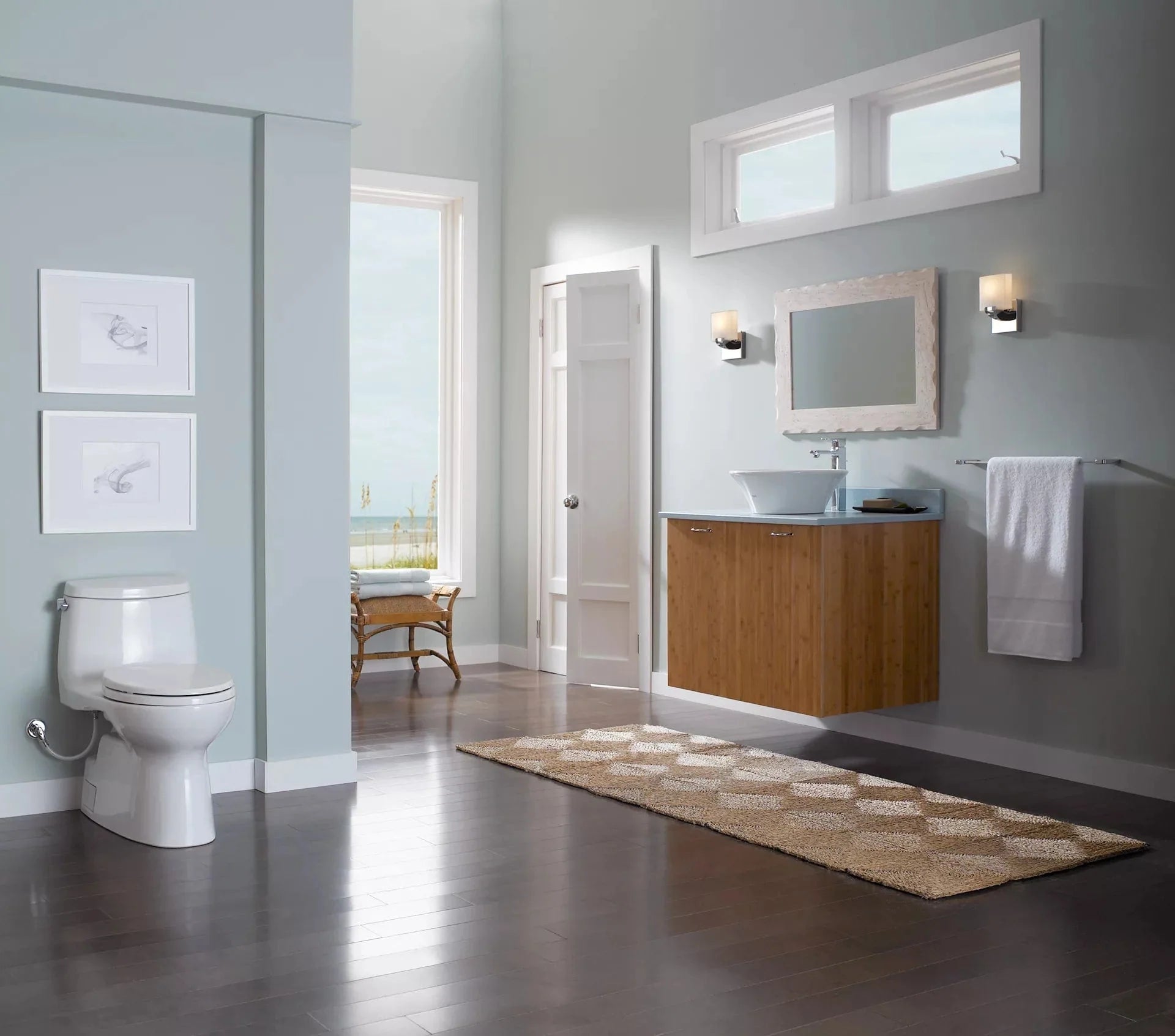 Elegant bathroom interior featuring TOTO Carlyle II One-Piece Toilet - 1.28 GPF beside a modern wooden vanity and large window view.