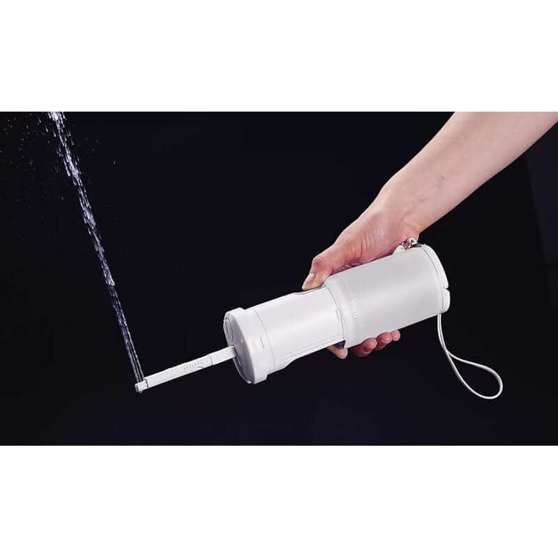 Hand using TOTO Travel Washlet, portable bidet with water stream, demonstrating easy use and compact design.