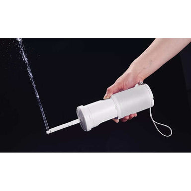 Hand using TOTO Travel Washlet, portable bidet with water stream, demonstrating easy use and compact design.